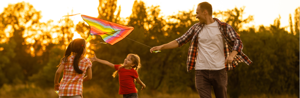 A father and two children playing with a kite.